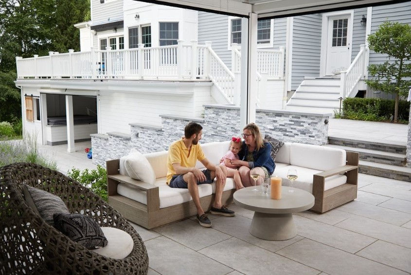 Family relaxing on a paver patio under an AmeriDex deck